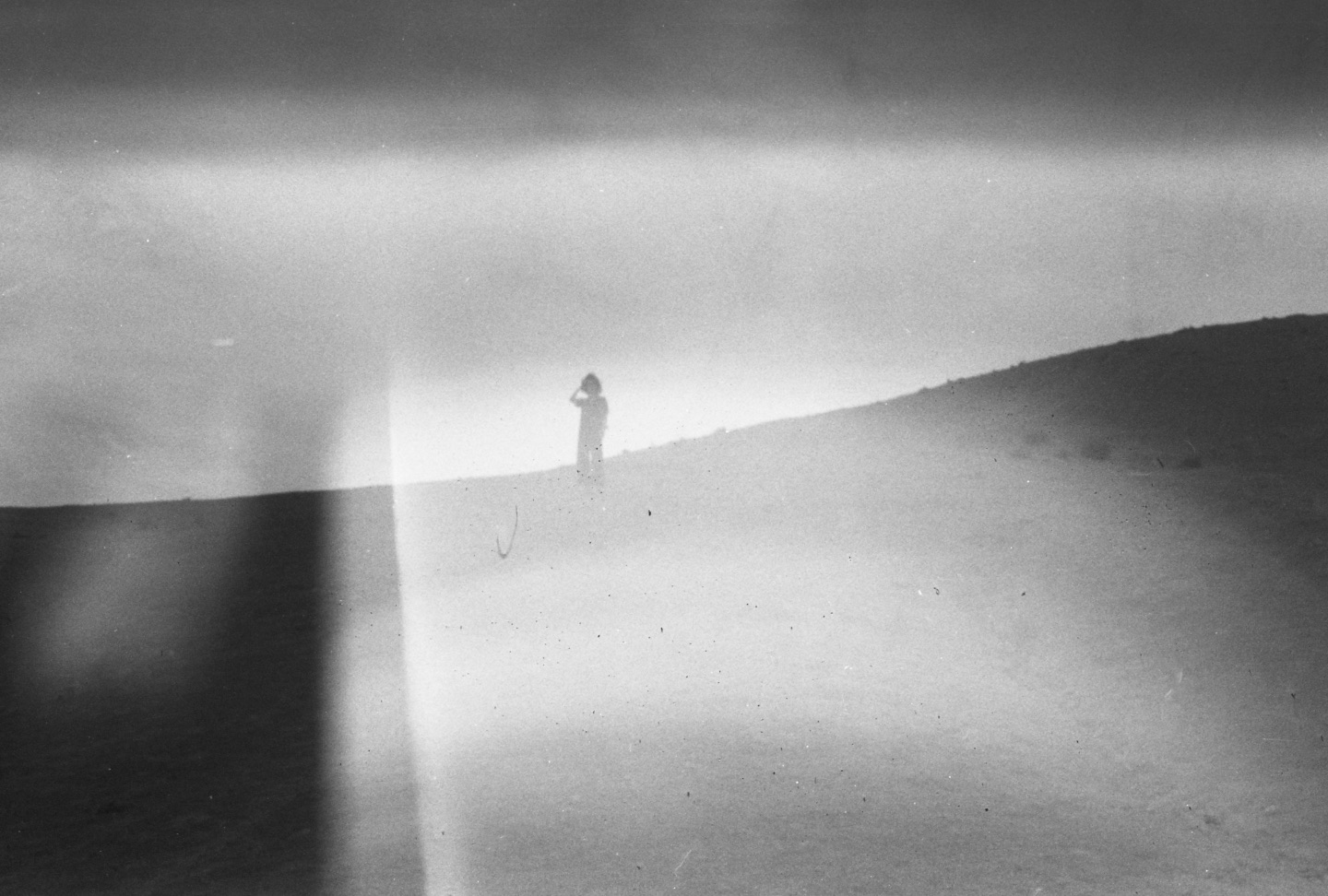 Black-and-white analog photograph of a figure on a dune