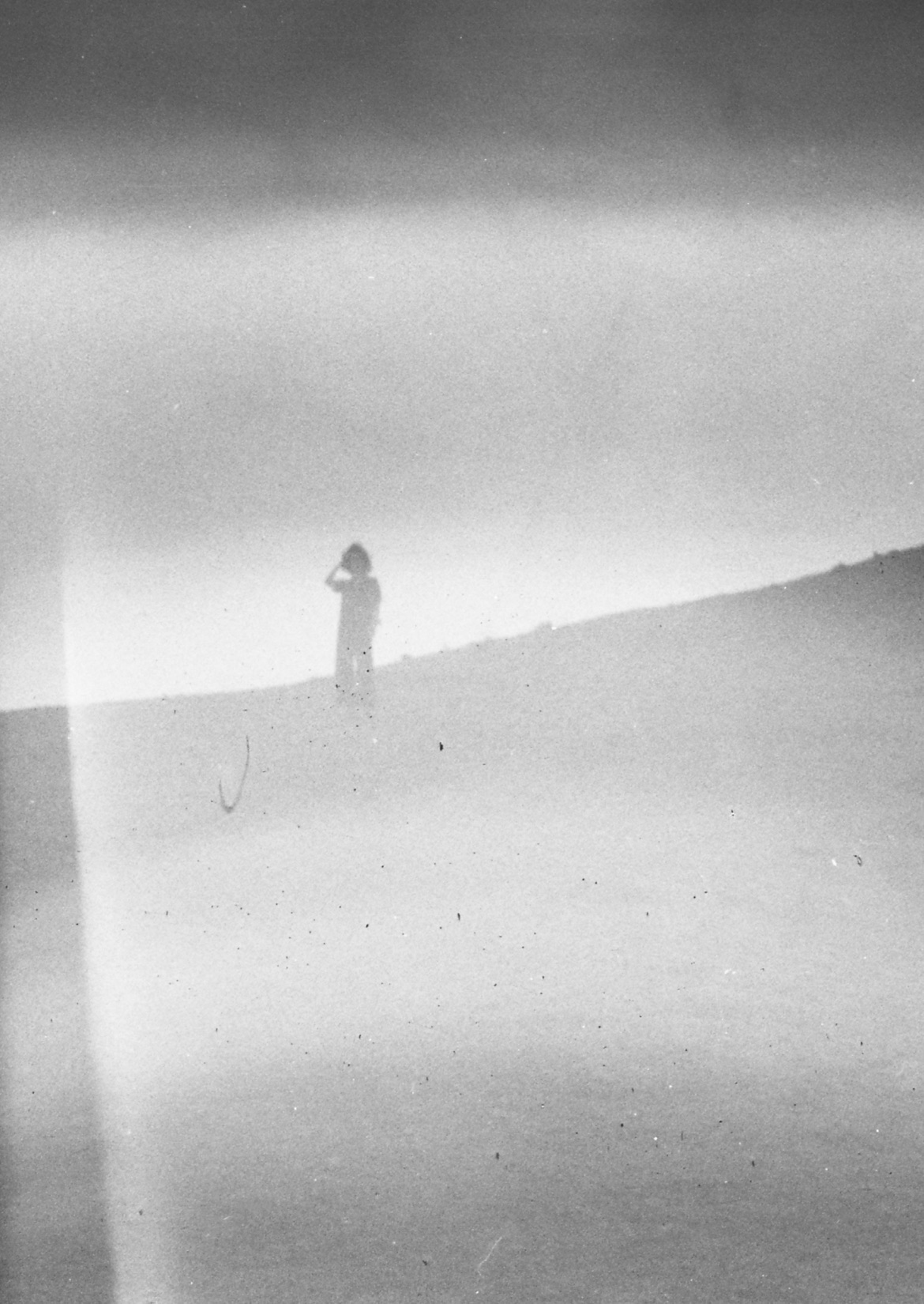 Black-and-white analog photograph of a figure on a dune