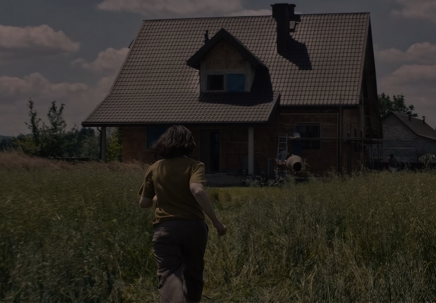 Film still of a girl running toward a house, with the animated brand shape